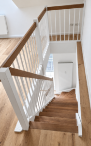 Weiße Holztreppe mit weißen Geländerstäben und Eichenhandlauf, Blick ins Treppenauge